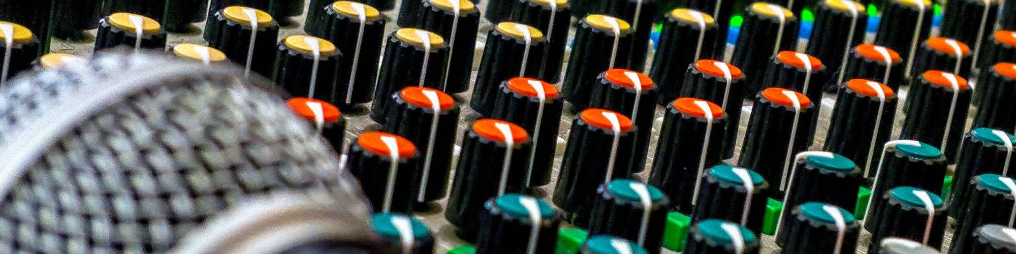 A microphone rests on a live sound mixing board